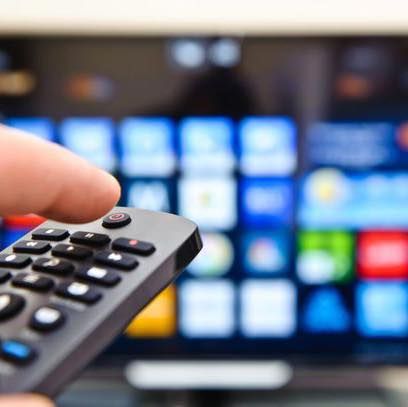 A Person Is Holding A Remote Control In Front Of A Television — Coastwide Antennas In Ourimbah, NSW